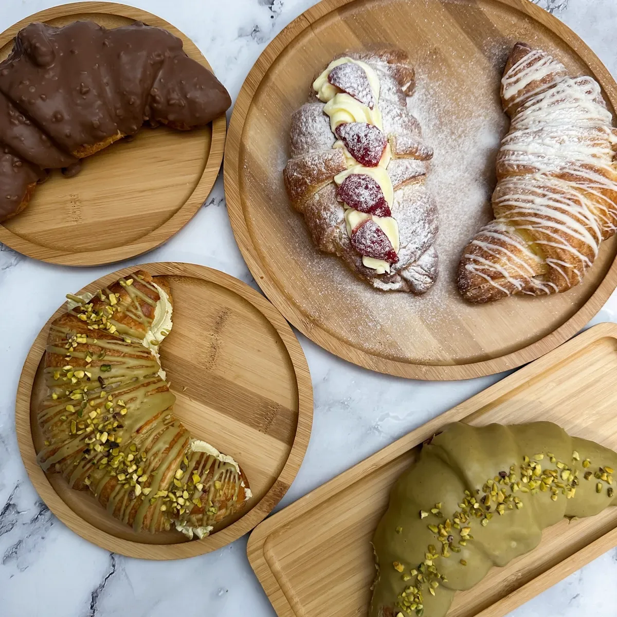 Croissante cu fistic sicilian, cu cremă și căpșuni, pe platouri de bambus