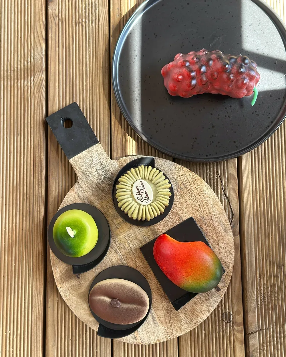 Deserturi în formă de fruct — mango, măr verde, fistic și fructul pasiunii, pe platou de lemn
