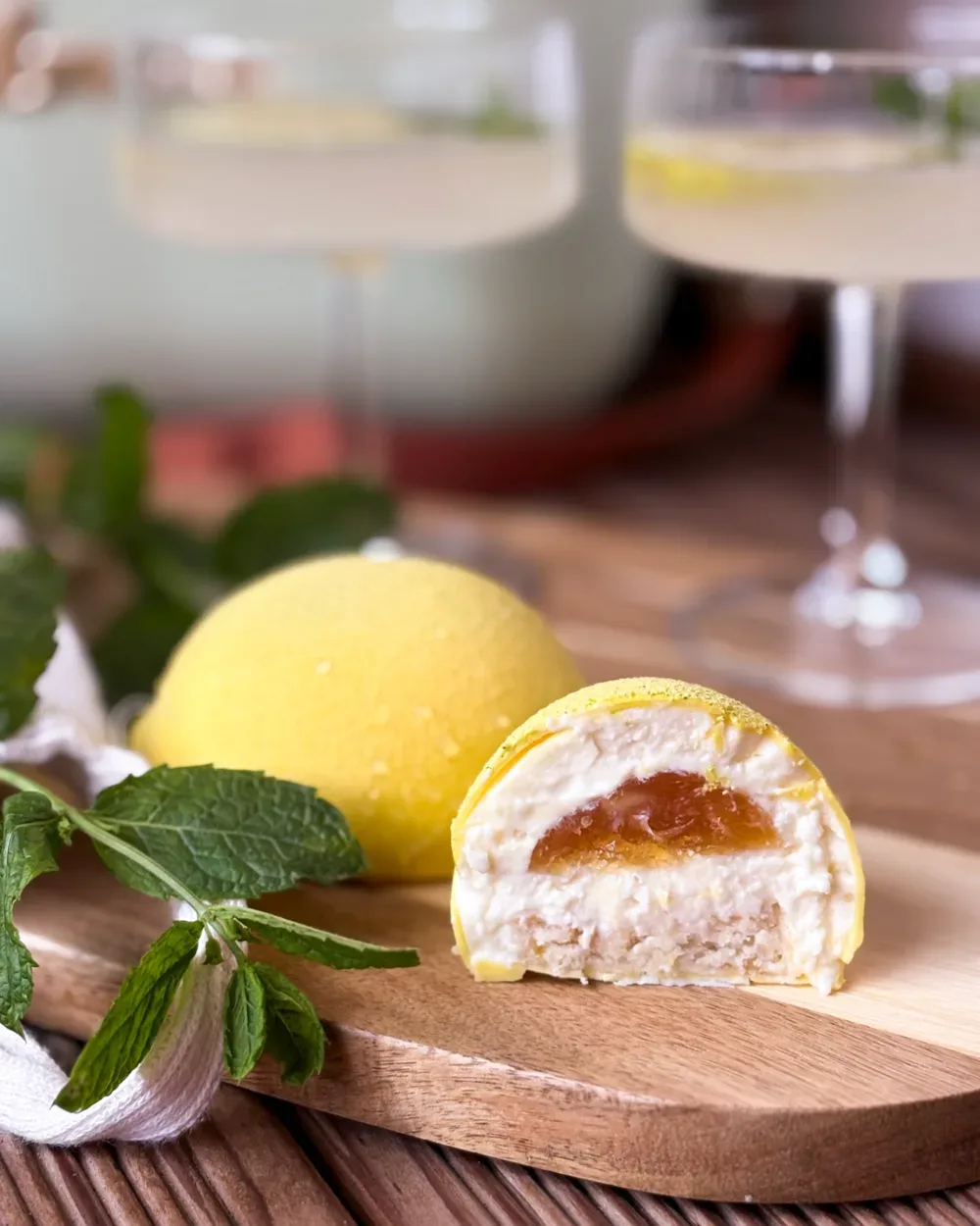 Desert în formă de lămâie, secționat, cu mousse de lămâie și insert de fruct, alături de mentă proaspătă
