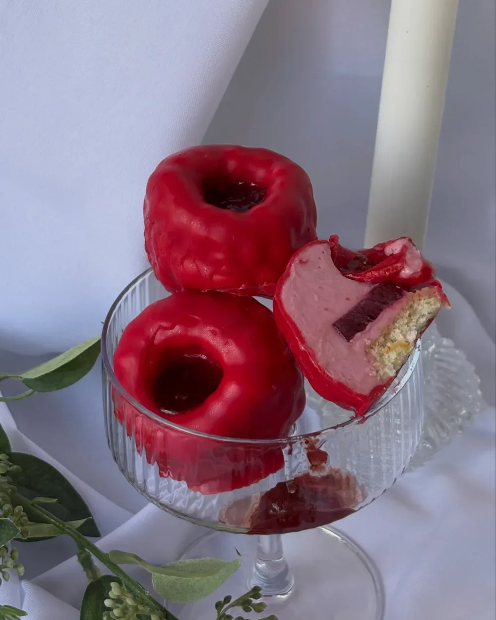 Deserturi glazurate roșu, în formă de fruct, cu mousse roz și insert de fructe de pădure, într-o cupă de sticlă